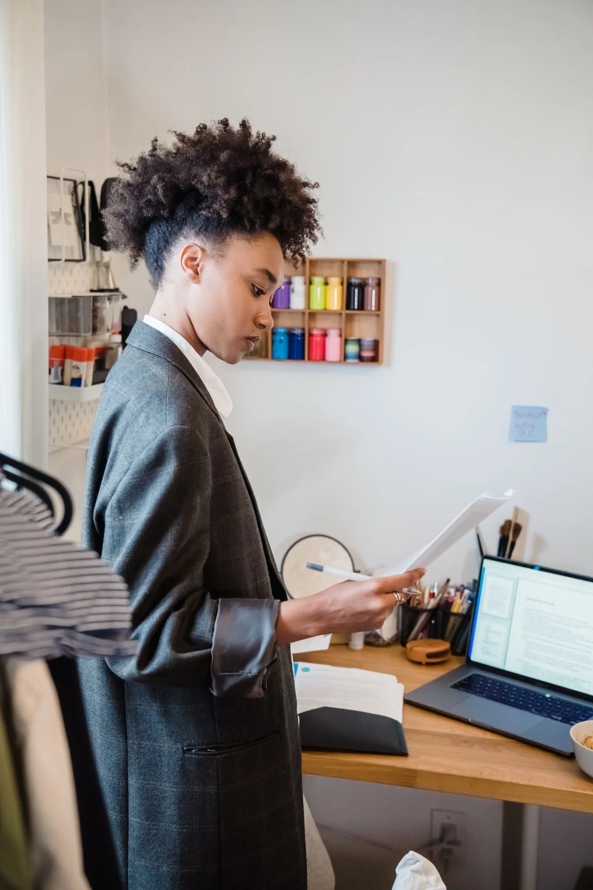 A woman reviewing paperwork beside her laptop.
